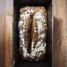 Eine Kastenform mit einem bemehlten Brot von oben fotografiert
