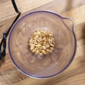 Unverarbeite Erdnüsse in einem Messbecher, bedeckt mit Öl