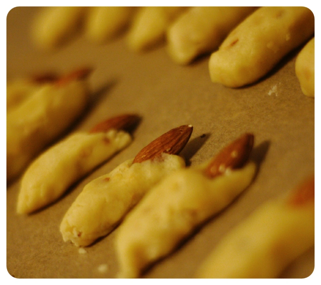 Kekse in Fingerform mit Mandeln als Fingernagel auf Backpapier